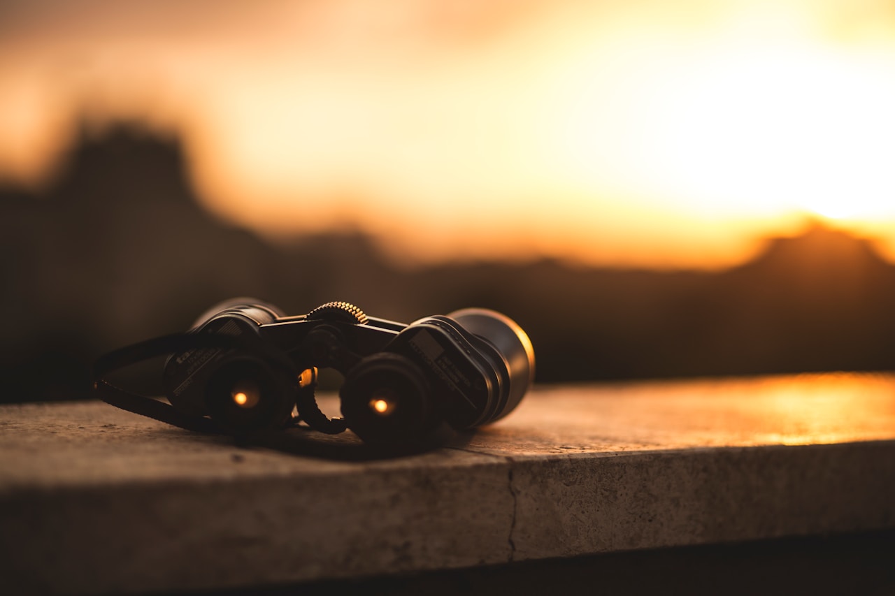 Binoculars on surface with sunset background